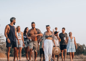 Group of friends walking together on a beach with arms around each other